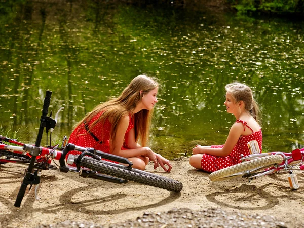 Happy mother with daughter rides bicycle and sitting on beach.