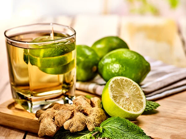 Glass with green transparent lime drink and ginger .