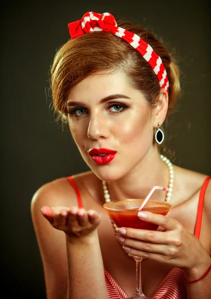 Girl in pin-up style drink martini cocktail and blow kiss .