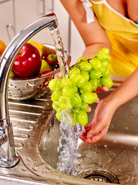 Woman washing fruit at kitchen.