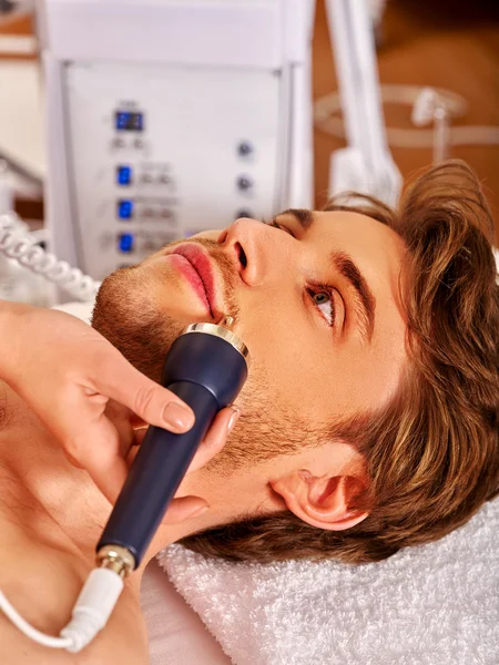 Man receiving electric facial peeling massage.