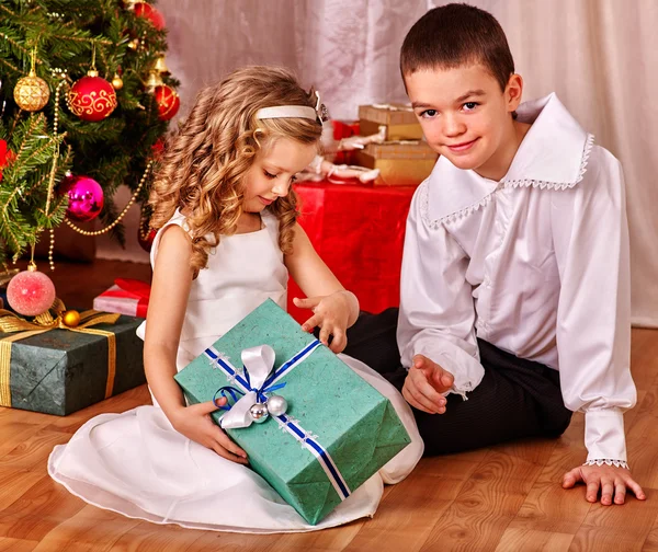 Children  receiving gifts under Christmas tree.