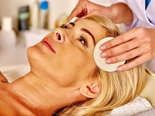 Woman middle-aged take face cleaning in spa salon.