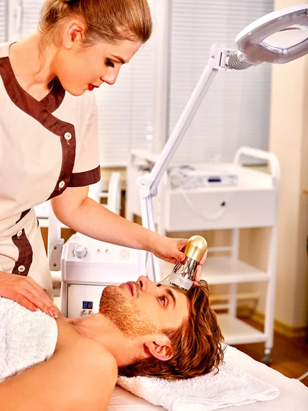 Young man receiving electric facial massage.