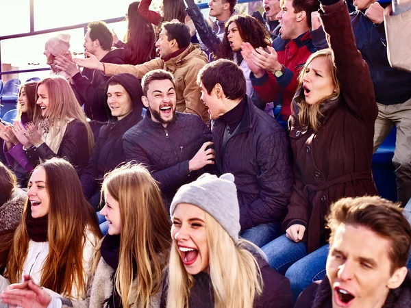 Sport fans clapping and singing on tribunes.