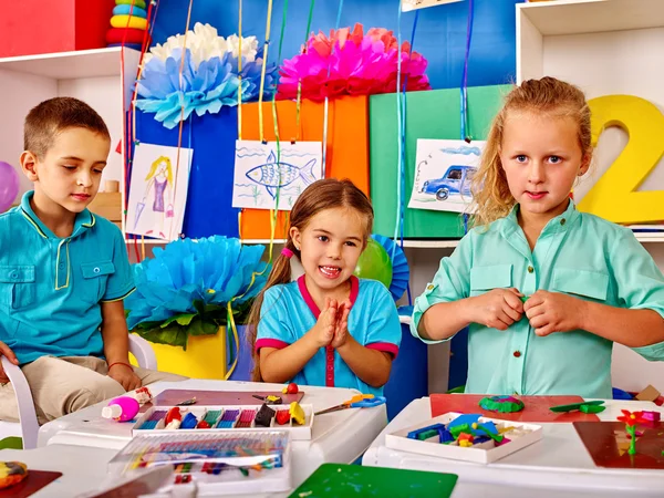 Group kids mold from plasticine  in kindergarten .