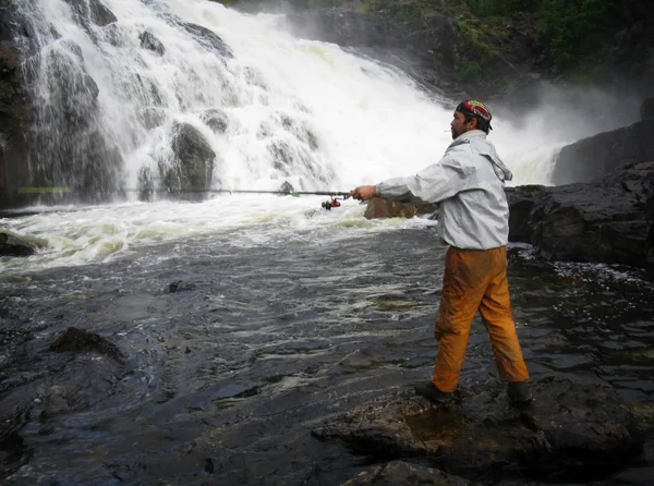 Man fishing near waterfall