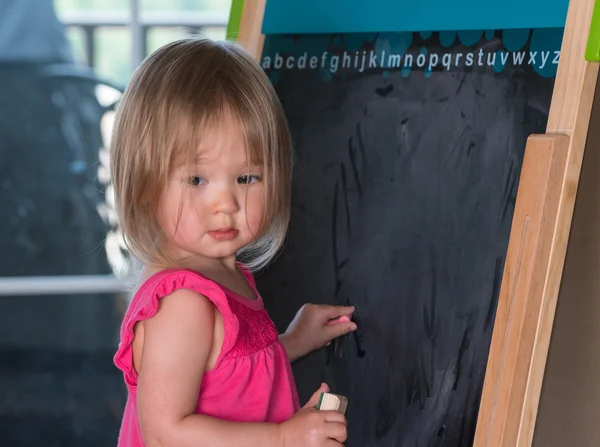 Young baby girl drawing at blackboard