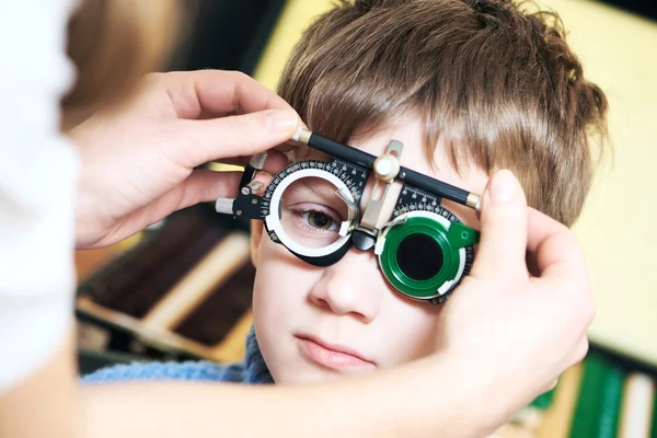 Optometrist doctor examines eyesight of child boy with phoropter