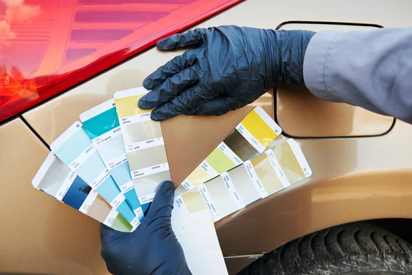 Colourist man selecting color of car with paint matching samples