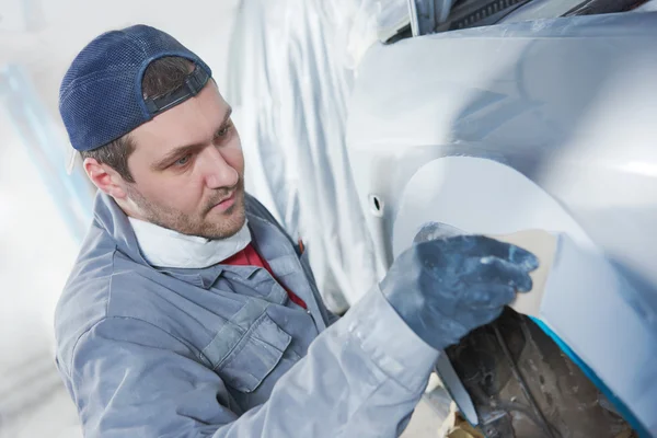 Auto repairman plastering autobody bonnet