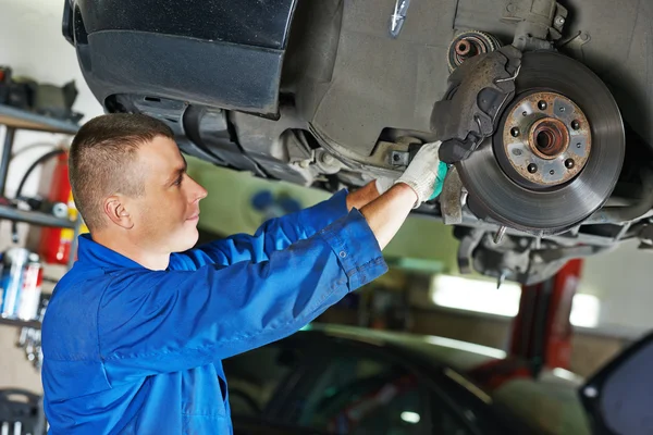 Auto mechanic at car suspension repairing