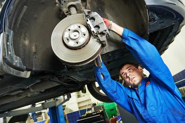 Auto mechanic at car brake shoes examining