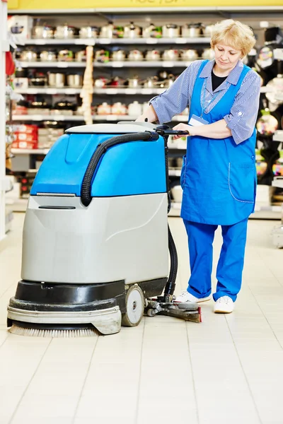 Worker cleaning store floor with machine