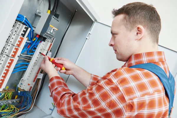 Electrician works with screwdriver in fuse box