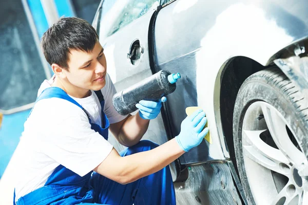 Worker preparing car body for paint