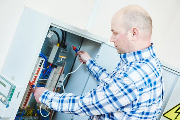 Electrician works with electric meter tester in fuse box