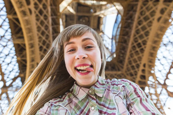 Girl taking a selfie under the Eiffel Tower in Paris