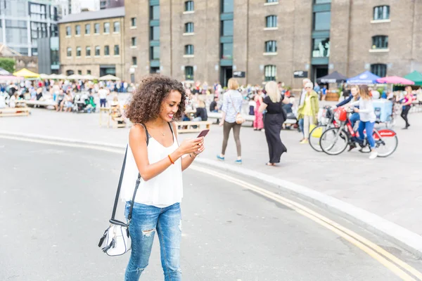 Young woman playing with augmented reality game in London