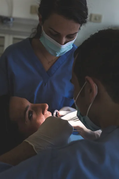 Dentist and Dental Assistant examining Patient teeth.