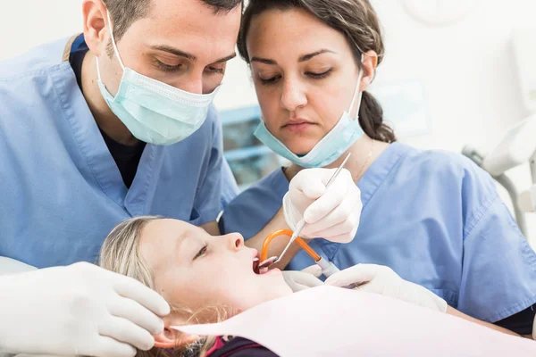 Dentist and Dental Assistant examining Young Girl teeth.