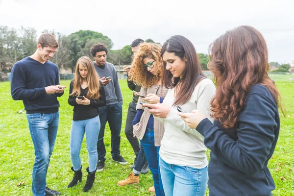 Multiethnic group of friends looking at their own smart phone