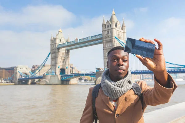 Man taking selfie in London with Tower Bridge on background