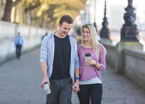 Young couple walking in London holding a cup of tea