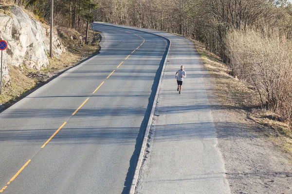 Man running outside along an empty road