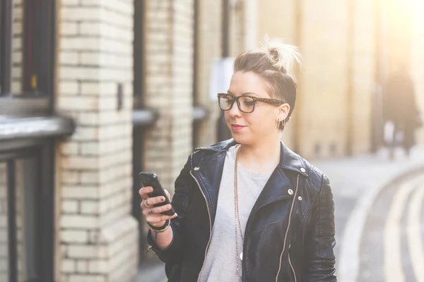 Girl walking down the street with her phone.