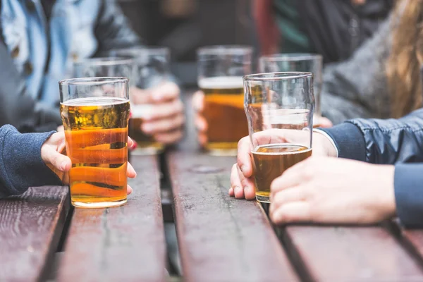 Hands holding glasses with beer on a table in London