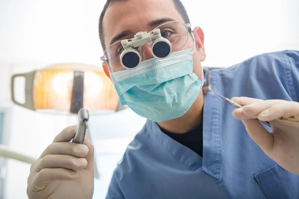 Dentist holding dental tools looking at camera.
