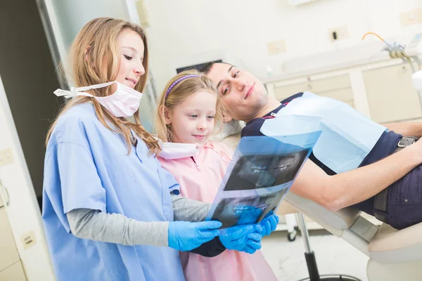 Little dentists looking at x-ray of adult patient