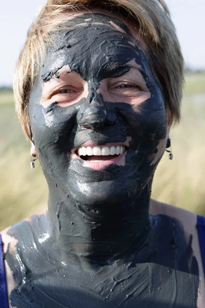 Smiling senior woman with mud face