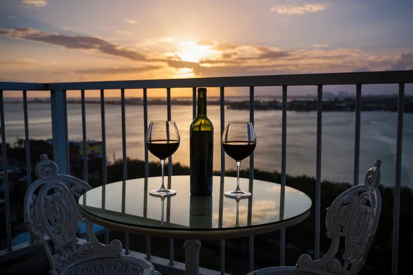Silhouette of bottle and glasses with red wine in sunset