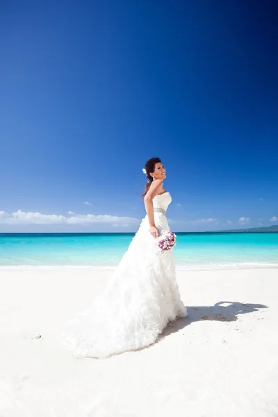 Beautiful bride on white sandy beach, smiling and feeling happin