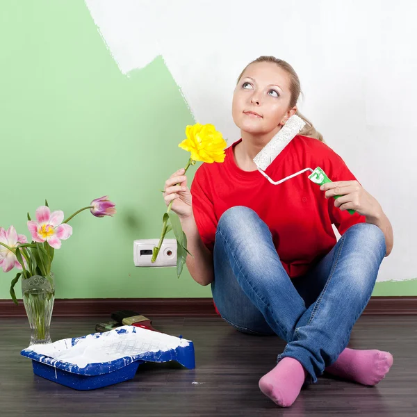 Young woman with flower and paint roller in hands