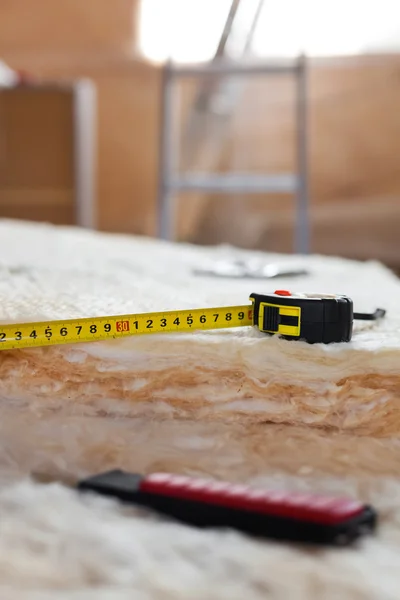 Measure tape and knife on mineral wool