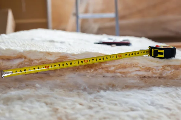 Measure tape and knife on mineral wool