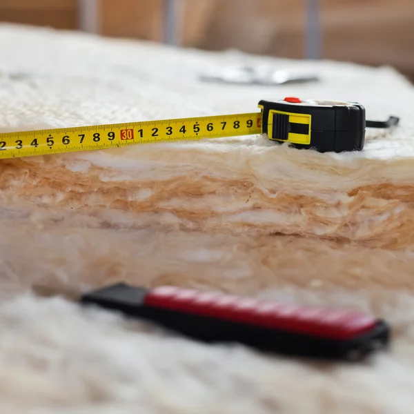 Measure tape and knife on mineral wool