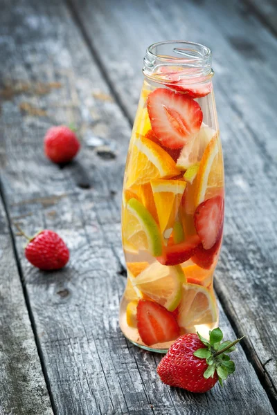 Fresh fruit detox water in bottle on wooden table