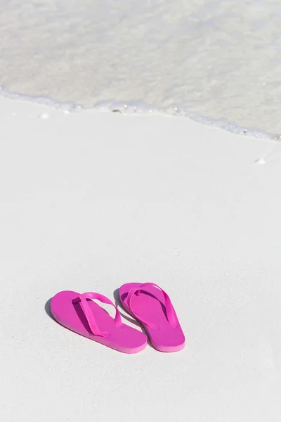 Pink flip flops on sandy beach