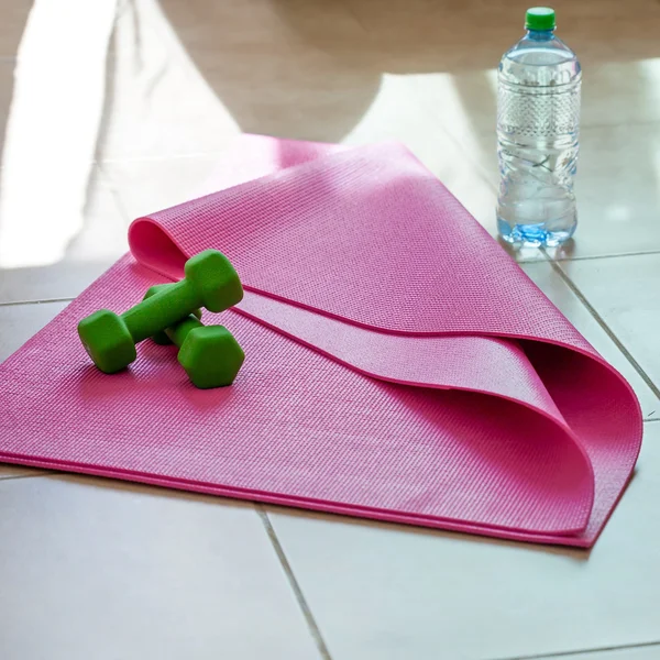 Two  dumbbells with mineral water on  yoga mat