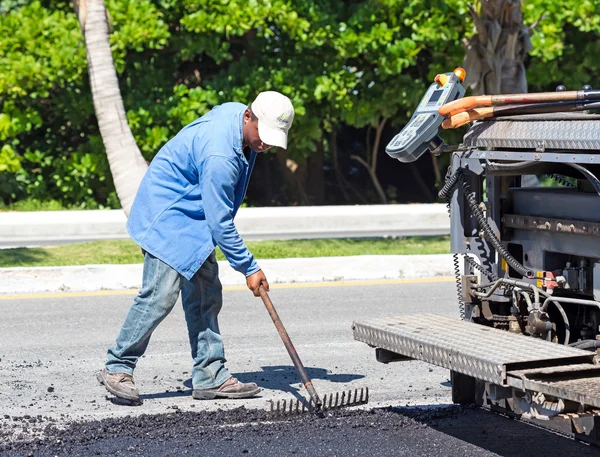 Worker making asphalt with rake