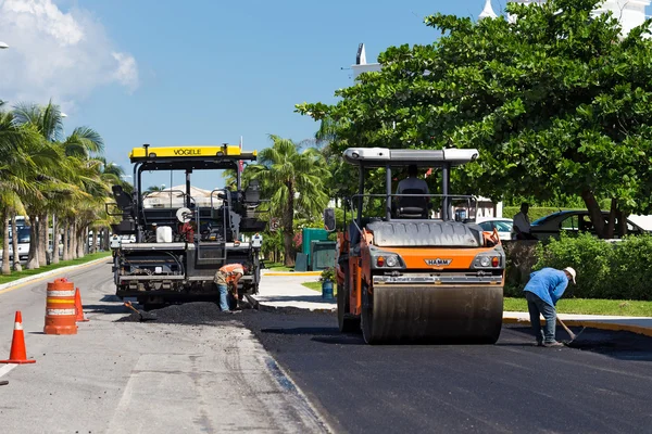 Road construction works with steamroller machine and asphalt fin
