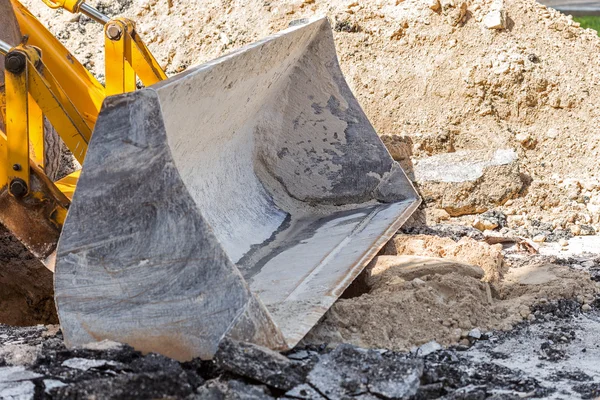 Road repair construction. Bulldozer bucket and broken asphalt