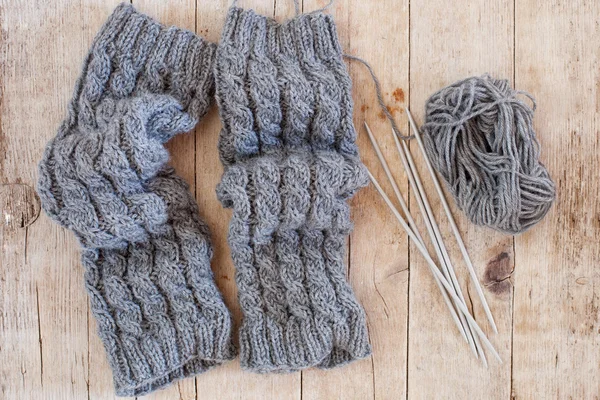 Wool grey legwarmers, knitting needles and yarn