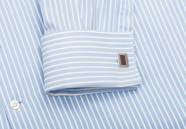 Sleeve of a striped blue shirt with a cuff link