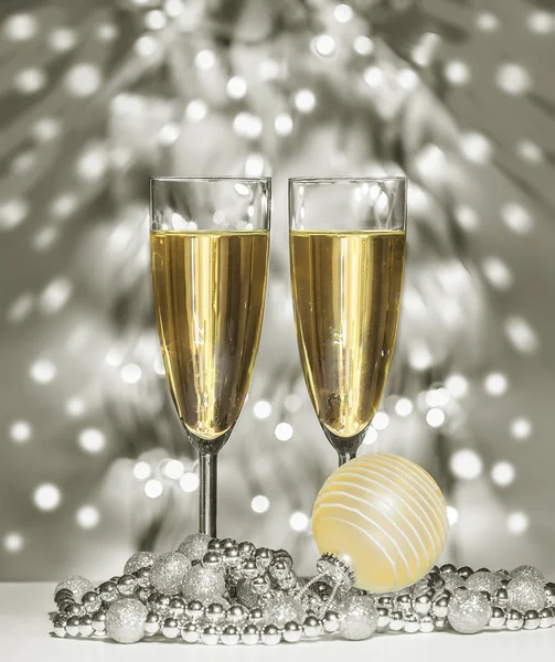 Gold christmas sphere, wine glasses against