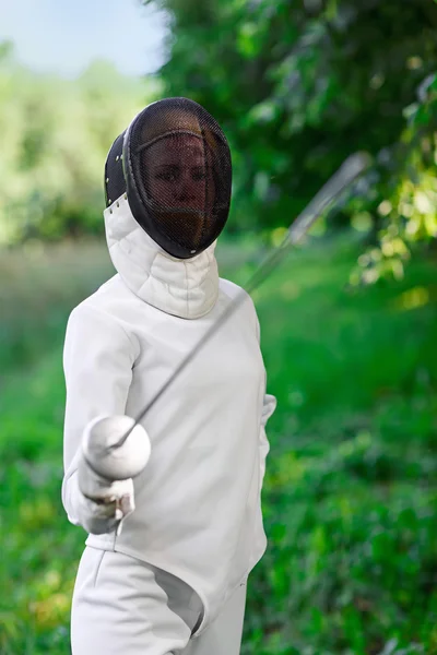 Fencer woman staying over beautiful nature background with rapie